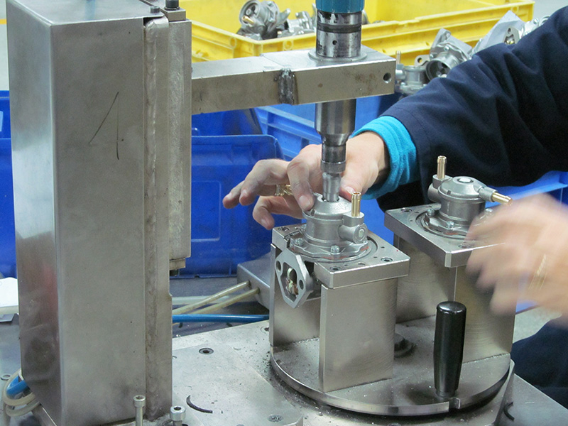 The worker is using a tool to make fuel pumps